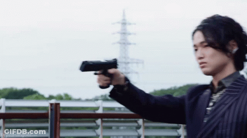 A Man In A Suit Is Pointing A Gun At A Fence . GIF