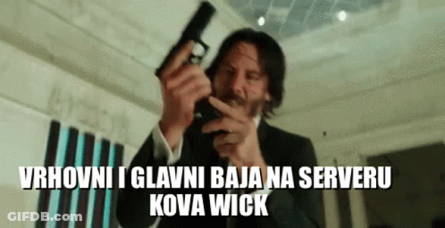 A Man In A Suit Is Pointing A Gun At The Camera With The Words Kova Wick Below Him . GIF