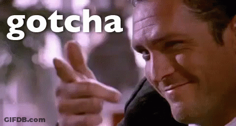 A Man In A Suit Is Pointing His Finger At The Camera With The Word Gotcha Behind Him . GIF