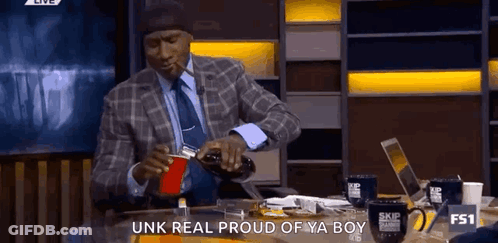 A Man In A Suit Is Pouring A Drink Into A Red Cup GIF