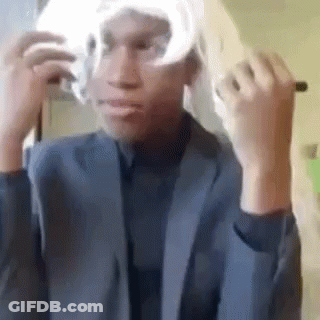 A Man In A Suit Is Putting On A Wig . GIF