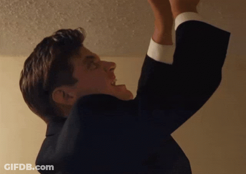A Man In A Suit Is Reaching Up To Reach Something GIF