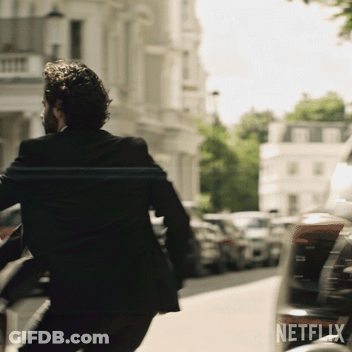 A Man In A Suit Is Running Down A Street With A Netflix Logo In The Corner GIF