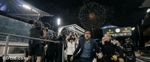A Man In A Suit Is Running Towards A Rolex Sign GIF