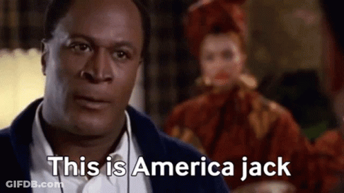 A Man In A Suit Is Saying This Is America Jack In Front Of A Woman In A Red Dress . GIF