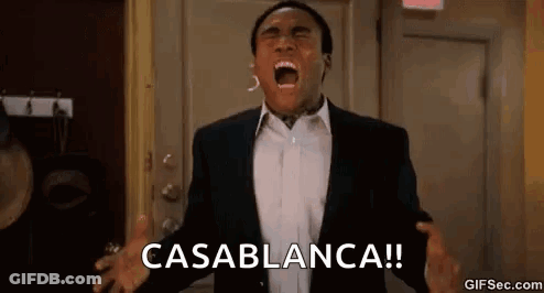 A Man In A Suit Is Screaming In Front Of A Door With His Mouth Open . GIF