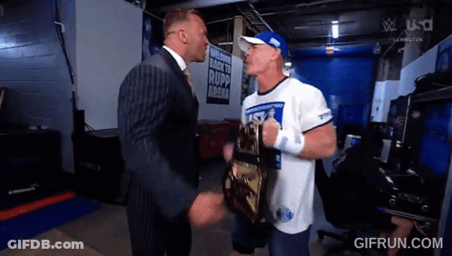 A Man In A Suit Is Shaking Hands With A Man In A White Shirt That Says ' Rapp Arena ' GIF