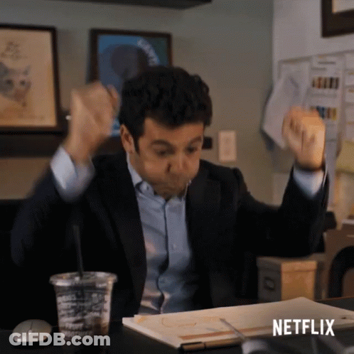 A Man In A Suit Is Sitting At A Desk With His Arms In The Air And A Netflix Logo On The Bottom GIF