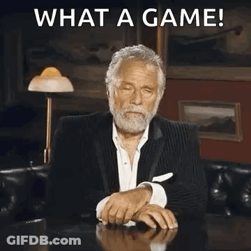 A Man In A Suit Is Sitting At A Table Covering His Face With His Hand And Making A Funny Face . GIF