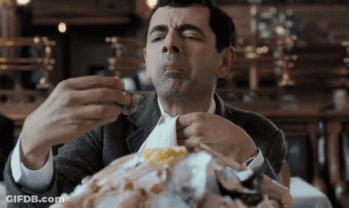 A Man In A Suit Is Sitting At A Table Eating A Large Amount Of Food . GIF