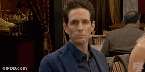 A Man In A Suit Is Sitting At A Table With A Fx Logo In The Corner GIF