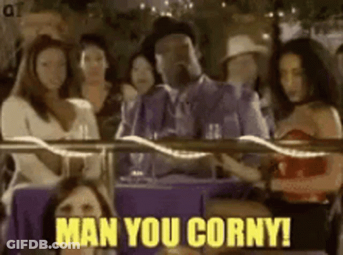 A Man In A Suit Is Sitting At A Table With A Group Of Women And Says Man You Corny . GIF