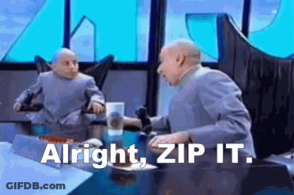 A Man In A Suit Is Sitting At A Table With A Microphone In His Hand . GIF