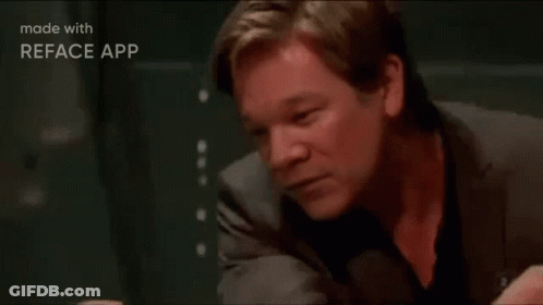 A Man In A Suit Is Sitting At A Table With His Head Resting On His Hand . GIF