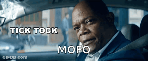 A Man In A Suit Is Sitting In A Car With The Words Tick Tock Mofo Below Him GIF