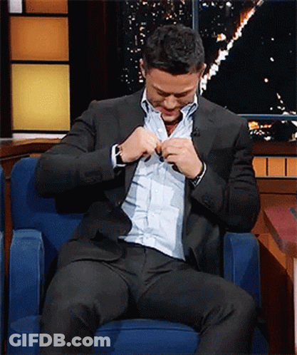 A Man In A Suit Is Sitting In A Chair GIF