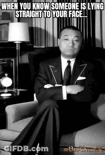 A Man In A Suit Is Sitting In A Chair With His Arms Crossed . GIF