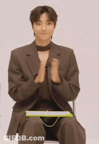 A Man In A Suit Is Sitting In A Chair With His Hands Folded GIF