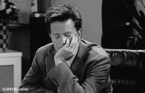 A Man In A Suit Is Sitting In A Chair With His Head Resting On His Hand . GIF
