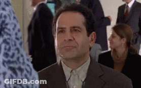 A Man In A Suit Is Sitting In A Crowd Of People GIF