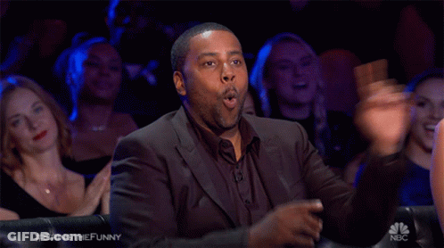 A Man In A Suit Is Sitting In Front Of A Crowd With The Hashtag Bringthefunny GIF
