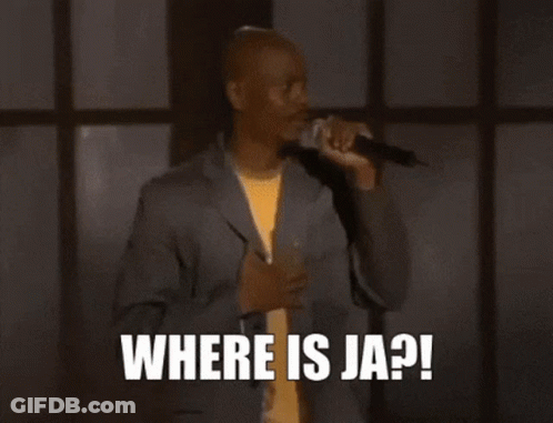 A Man In A Suit Is Sitting In Front Of A Microphone And Says `` Help Me Ja Rule '' . GIF