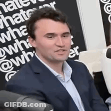 A Man In A Suit Is Sitting In Front Of A Microphone And Talking . GIF