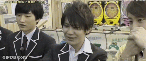 A Man In A Suit Is Sitting In Front Of A Sign That Says Hk In Hk GIF