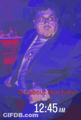 A Man In A Suit Is Sitting In Front Of A Sign That Says It 'S About That Time GIF