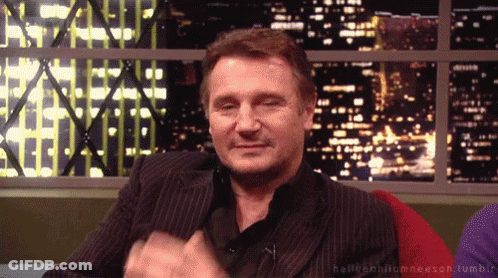 A Man In A Suit Is Sitting In Front Of A Window With A Cityscape In The Background GIF
