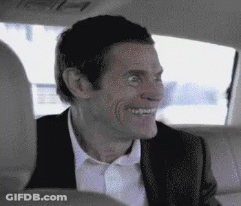 A Man In A Suit Is Sitting In The Back Seat Of A Car And Smiling . GIF