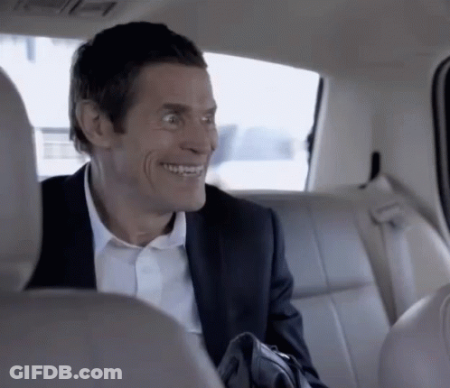 A Man In A Suit Is Sitting In The Back Seat Of A Car Smiling GIF