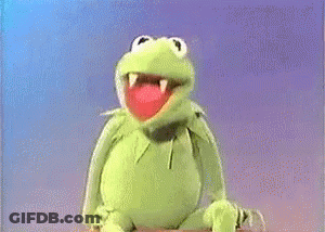 A Man In A Suit Is Sitting Next To A Muppet Frog . GIF