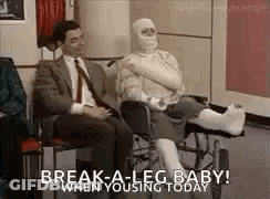 A Man In A Suit Is Sitting Next To A Woman In A Wheelchair With A Cast On Her Leg . GIF