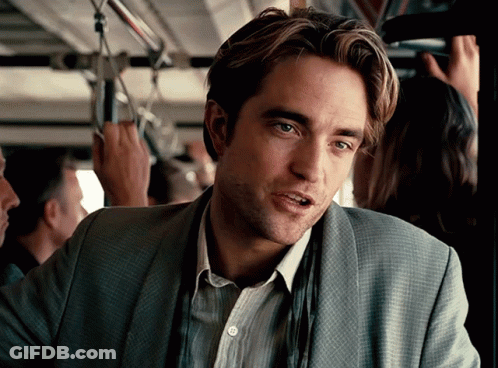 A Man In A Suit Is Sitting On A Bus Looking At The Camera GIF