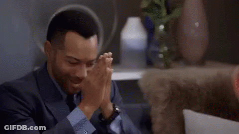 A Man In A Suit Is Sitting On A Couch And Adjusting His Sleeves . GIF