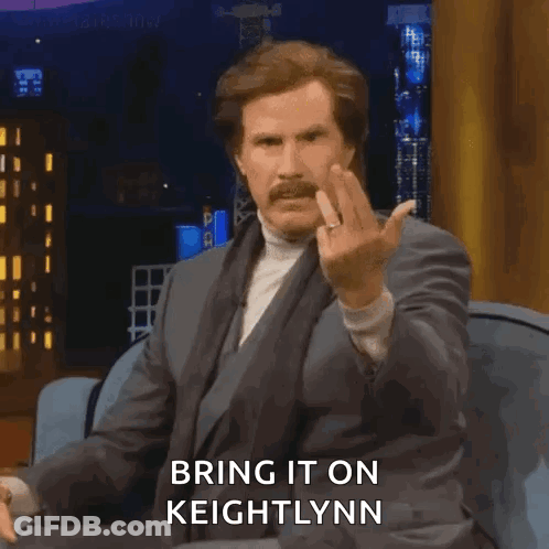 A Man In A Suit Is Sitting On A Couch And Giving The Middle Finger While Saying Bring It On Keightlynn . GIF