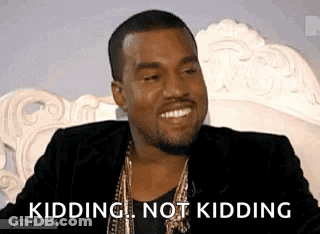 A Man In A Suit Is Sitting On A Couch And Smiling While Saying `` Kidding , Not Kidding '' . GIF