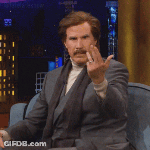 A Man In A Suit Is Sitting On A Couch Giving The Middle Finger GIF