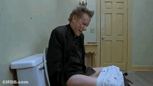 A Man In A Suit Is Sitting On A Toilet With His Pants Down And His Face Covered In Spots . GIF