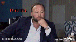 A Man In A Suit Is Sitting With His Hand On His Chin And The Word Patriot Is On The Screen GIF