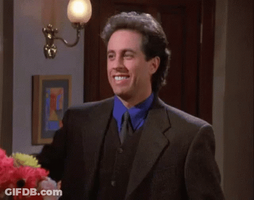 A Man In A Suit Is Smiling And Holding Up A Sign That Says " I Like " GIF