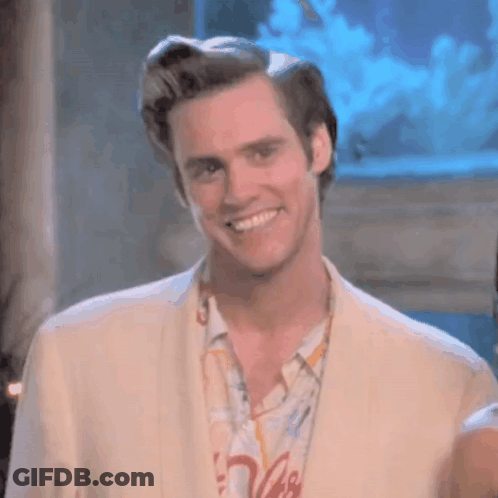 A Man In A Suit Is Smiling And Looking At The Camera . GIF