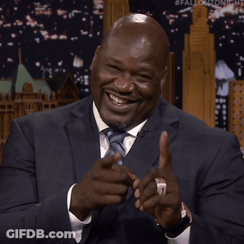 A Man In A Suit Is Smiling And Pointing At The Camera GIF