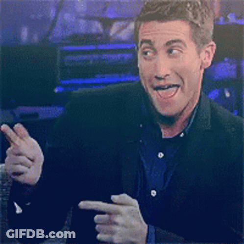 A Man In A Suit Is Smiling And Pointing GIF