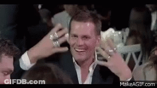 Man In Suit Smiling In Crowd With Hands To Head GIF