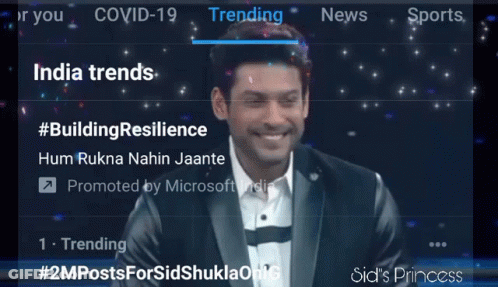 A Man In A Suit Is Smiling In Front Of A Screen That Says Trending India Trends GIF