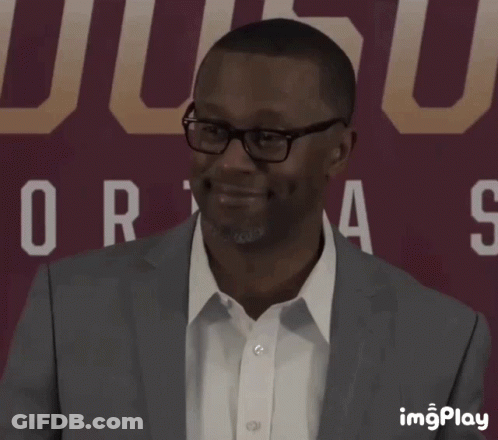 A Man In A Suit Is Smiling In Front Of A Sign That Says Ucsd GIF