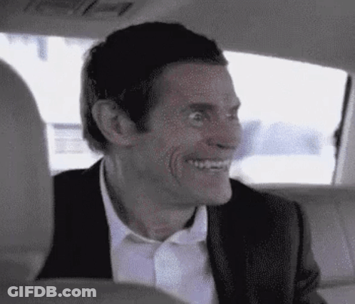 A Man In A Suit Is Smiling In The Back Seat Of A Car . GIF