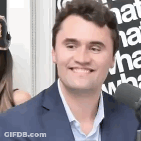 A Man In A Suit Is Smiling Into A Microphone . GIF